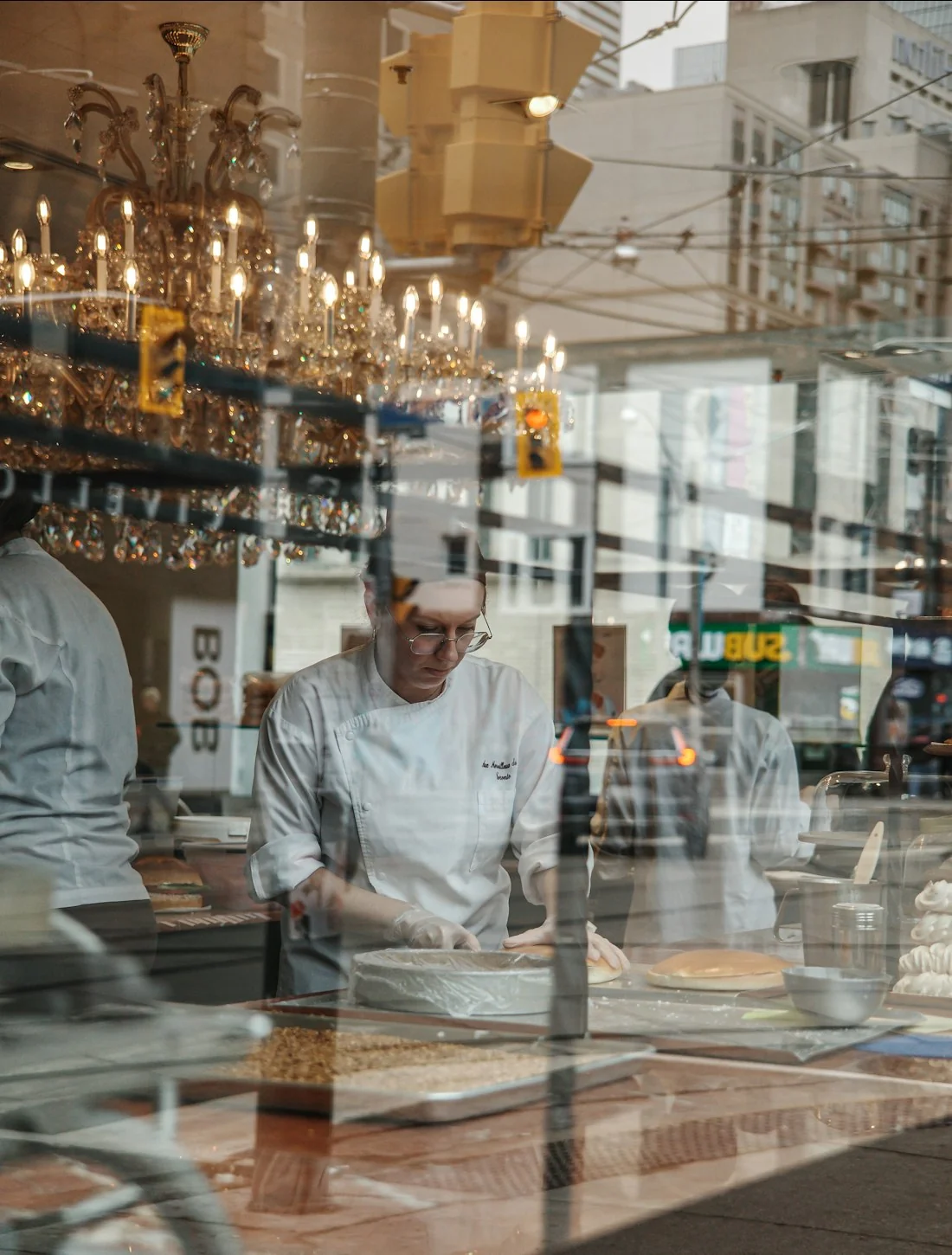 Un chef dresse des assiettes derrière le passe d’une cuisine
