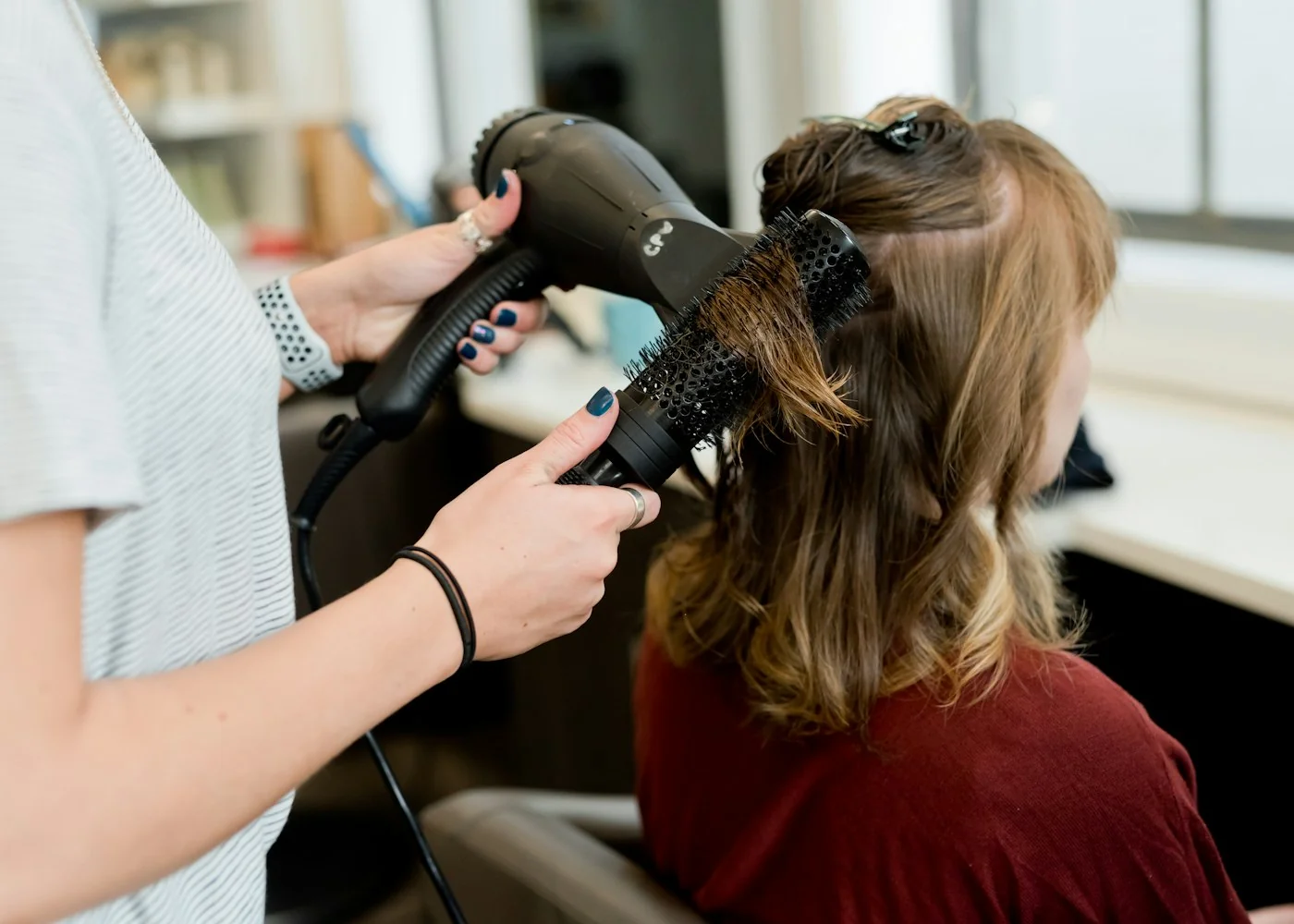 Une coiffeuse sèche les cheveux d’une cliente au salon