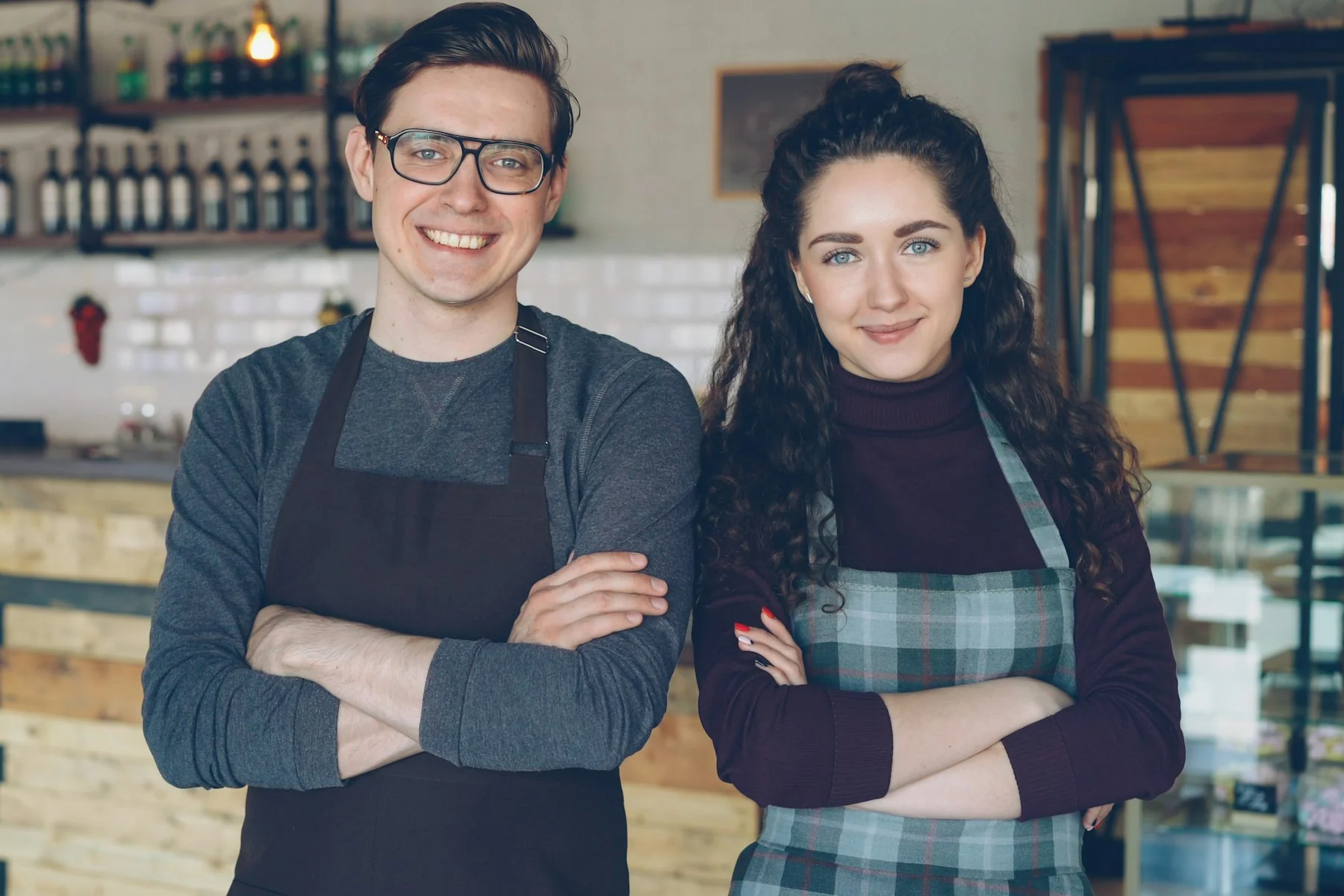 Deux commerçants souriants derrière le comptoir de leur café